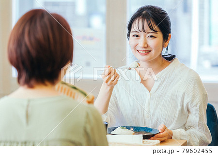 女友達とおしゃべりしながらランチする女性 79602455