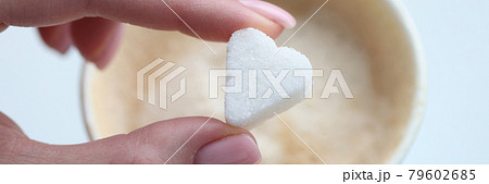 Woman putting coffee sugar cube in shape of heart closeup Woman putting coffee sugar cube in shape of heart closeup 79602685