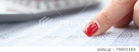 Woman pointing her index finger at numbers in table and counting on calculator closeup Woman pointing her index finger at numbers in table and counting on calculator closeup 79603369