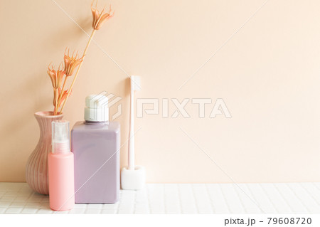 Bathroom bottles, toothbrush, vase of plant on white mosaic tile table. pink wall background. Skin care and spa concept. Home interior 79608720