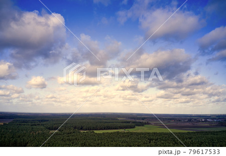 Blue sky with white clouds over the cultural landscape in the north of Germany with forests, meadows and fields, aerial view with the drone Blue sky with white clouds over the cultural landscape in the north of Germany with forests, meadows and fields, aerial view with the drone 79617533