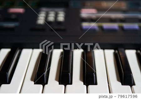 Keyboard of an electric piano, control unit out of focus in the background 79617596