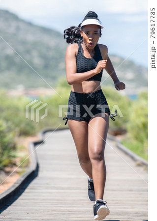 Vigorous afro american woman exercising along a wooden runway: Selective focus. lifestyle concept. Vigorous afro american woman exercising along a wooden runway: Selective focus. lifestyle concept. 79617785