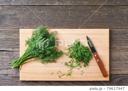 Fresh chopped green dill leaves on a cutting board, top view. Fresh chopped green dill leaves on a cutting board, top view. 79617947