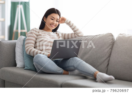 Happy Young Asian Woman Watching Movies Online On Laptop At Home Happy Young Asian Woman Watching Movies Online On Laptop At Home 79620697
