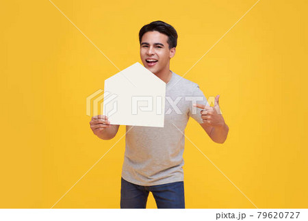 Handsome excited Asian man holding house cutout isolated on yellow background. 79620727