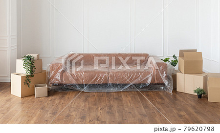 Living room with covered sofa, stacks of boxes during relocation 79620798