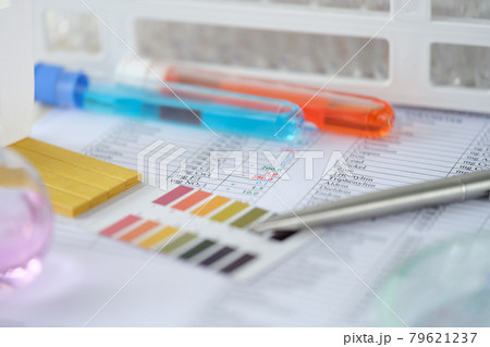 Chemical test tubes with blue and orange liquid with analysis results on table closeup 79621237
