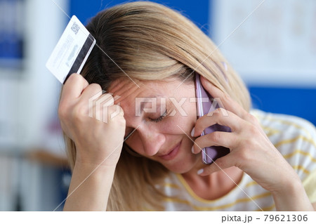 Upset woman talking on phone and holding plastic bank card 79621306