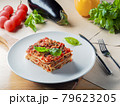 Piece of lasagna on white plate with knife and 79623205