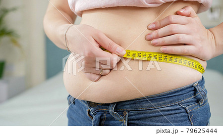 Closeup of overweight woman using measuring tape. Concept of dieting, unhealthy lifestyle, overweight and obesity 79625444