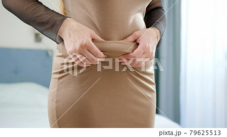 Closeup of obese woman in dress holding fat folds on belly 79625513