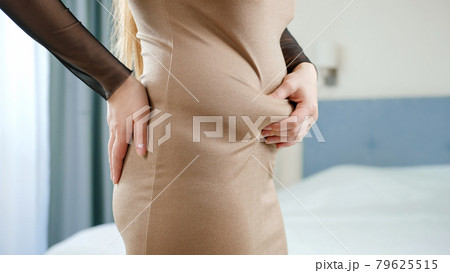 Young obese woman with big belly wearing dress holding fat folds on stomach. Concept of excessive weight, obese female, dieting and overweight problems Young obese woman with big belly wearing dress holding fat folds on stomach. Concept of excessive weight, obese female, dieting and overweight problems 79625515