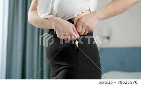 Young obese woman trying to fit and zip up tight small dress. Concept of excessive weight, obese female, dieting and overweight problems Young obese woman trying to fit and zip up tight small dress. Concept of excessive weight, obese female, dieting and overweight problems 79625570