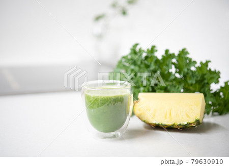Kale and pineapple smoothie in a glass isolated on mable countertop. Healthy food concept 79630910