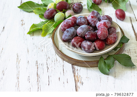 Seasonal food background. Ripe juicy plums in a bowl on a rustic wooden table. Copy space. 79632877