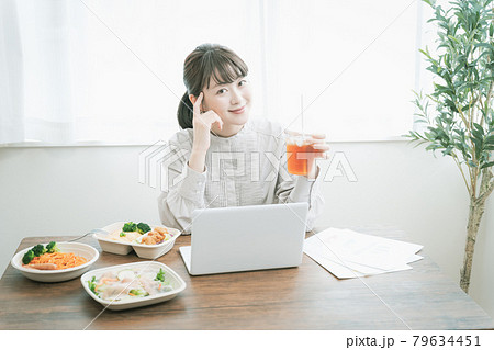デリバリーフードを食べながらテレワークする女性 79634451