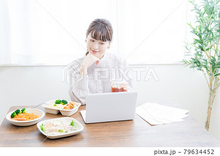デリバリーフードを食べながらテレワークする女性 デリバリーフードを食べながらテレワークする女性 79634452