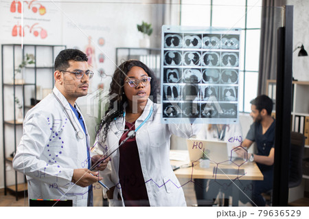 International doctors discussing results of x ray scan International doctors discussing results of x ray scan 79636529