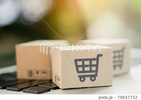Shopping online. Cardboard box with a shopping cart logo on laptop keyboard. Shopping service on The online web. offers home delivery. copy space. Shopping online. Cardboard box with a shopping cart logo on laptop keyboard. Shopping service on The online web. offers home delivery. copy space. 79637732