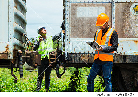 Inspector Engineering wearing helmet and vest worker unifrom checking railway construction work on rail track. Asian workers and coworkers stand beside old train bogies. Inspector Engineering wearing helmet and vest worker unifrom checking railway construction work on rail track. Asian workers and coworkers stand beside old train bogies. 79638707