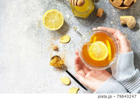 Woman holds a hot cup of ginger tea. Top view flat lay. Free space for your text. Woman holds a hot cup of ginger tea. Top view flat lay. Free space for your text. 79643247