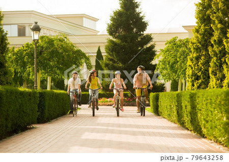 Friends are relaxing by cycling together. 79643258