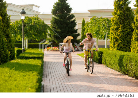 Cheerful couple riding bicycles in park. 79643263