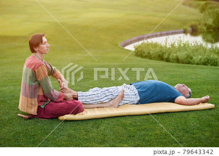Man doing feet thai massage to senior man. 79643342