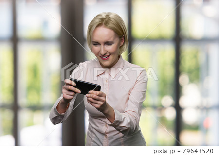 Funny blonde woman plays on her smartphone. Funny blonde woman plays on her smartphone. 79643520