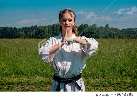 teenage girl training karate kata outdoors, greetings oss 79643899