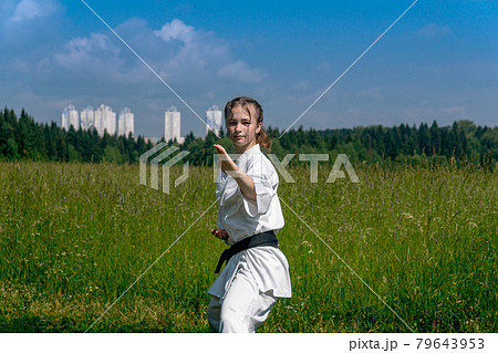 teenage girl training karate kata outdoors, performs soto uke or outside block 79643953