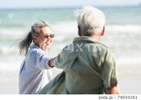 senior man and woman couple holding hands walking to the beach sunny with bright blue sky 79650261