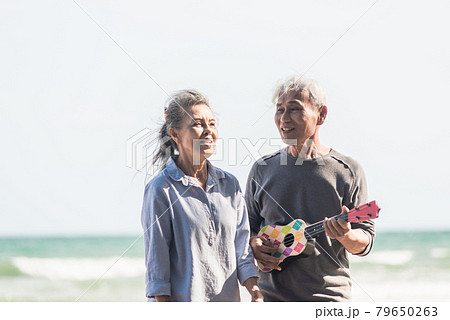 Happy senior couple relaxing outdoors singing and playing acoustic guitar at beach near sea sunny day Happy senior couple relaxing outdoors singing and playing acoustic guitar at beach near sea sunny day 79650263
