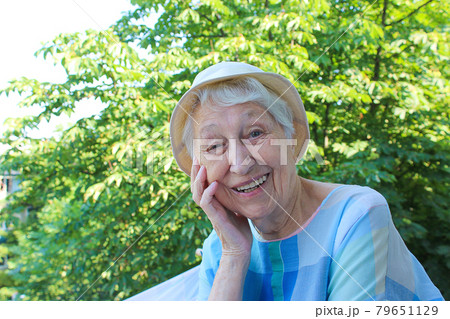 Positive senior woman watering decorative plants on balcony 79651129