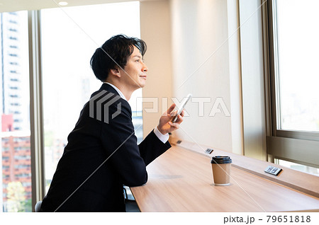 窓際のフリースペースでスマホを操作する男性　撮影協力「＋SHIFT NOGIZAKA」 79651818