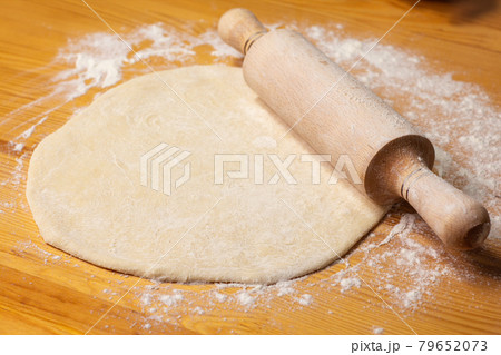 Pizza dough on wooden background. Rolling-pin and flour. Selective focus Pizza dough on wooden background. Rolling-pin and flour. Selective focus 79652073