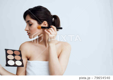 brunette wears brush makeup face care light background brunette wears brush makeup face care light background 79654540