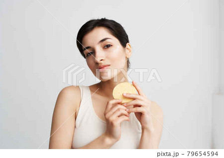 brunette in a white t-shirt Sponge in hands skin care light background brunette in a white t-shirt Sponge in hands skin care light background 79654594