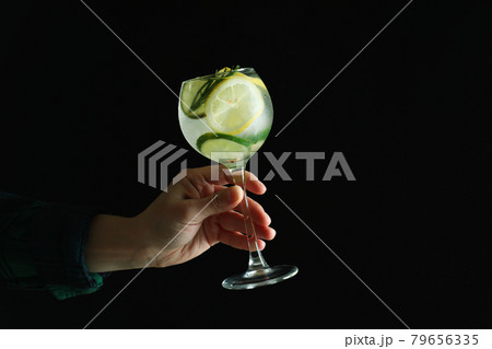Female hand hold glass of cocktail with citrus on dark background 79656335