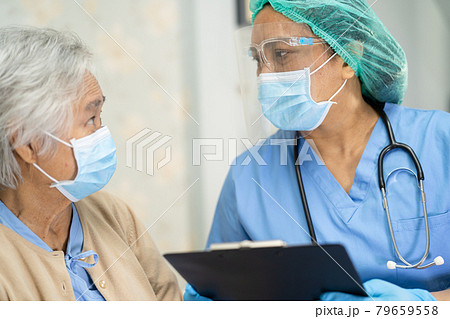 Asian doctor wearing face shield and PPE suit new normal to check patient protect safety infection Covid-19 Coronavirus outbreak at quarantine nursing hospital ward. 79659558