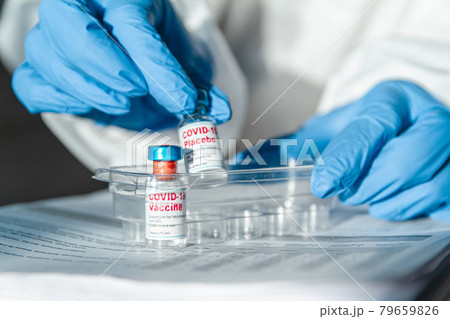 Doctor or nurse in protective suit holding covid 19 vaccine and 79659826