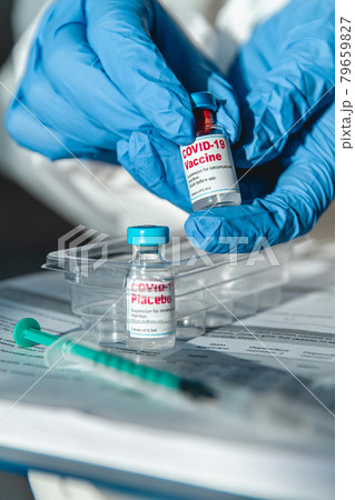 Doctor or nurse in protective suit holding covid 19 vaccine and Doctor or nurse in protective suit holding covid 19 vaccine and 79659827