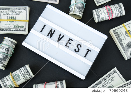 Lightbox board with word INVEST in black letters around US dollar banknotes. Money, Business, finance, investment, saving 79660248