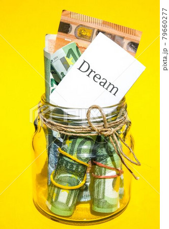 Glass jars filled with Euro bills, savings inside glass jar, money isolated on yellow background. Paper note written word DREAM. Business budget of wealth Glass jars filled with Euro bills, savings inside glass jar, money isolated on yellow background. Paper note written word DREAM. Business budget of wealth 79660277