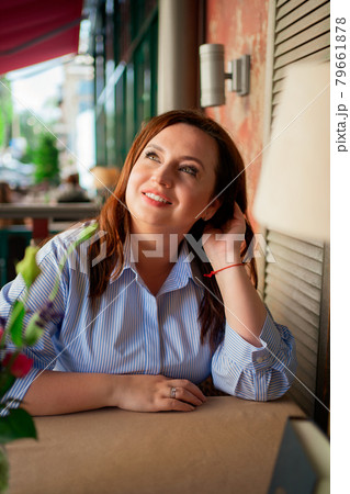 Portrait of an attractive woman in a blue dress with long hair at a cafe table  79661878
