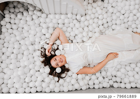 top view. an attractive woman in white clothes lies in a dry pool with balls top view. an attractive woman in white clothes lies in a dry pool with balls 79661889