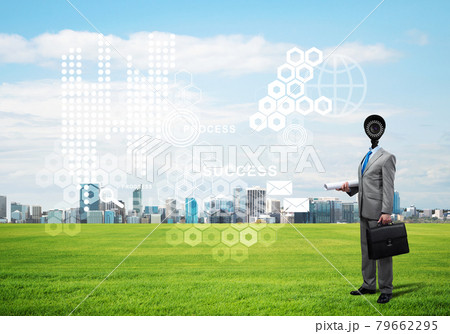 Camera headed man standing on green grass against modern cityscape 79662295