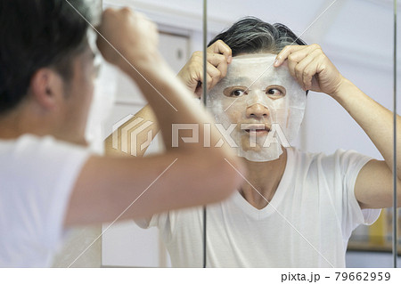 鏡を見ながらシートパックをつける中高年男性 79662959