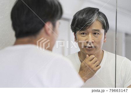 鏡で顔を見る50代の男性 鏡で顔を見る50代の男性 79663147